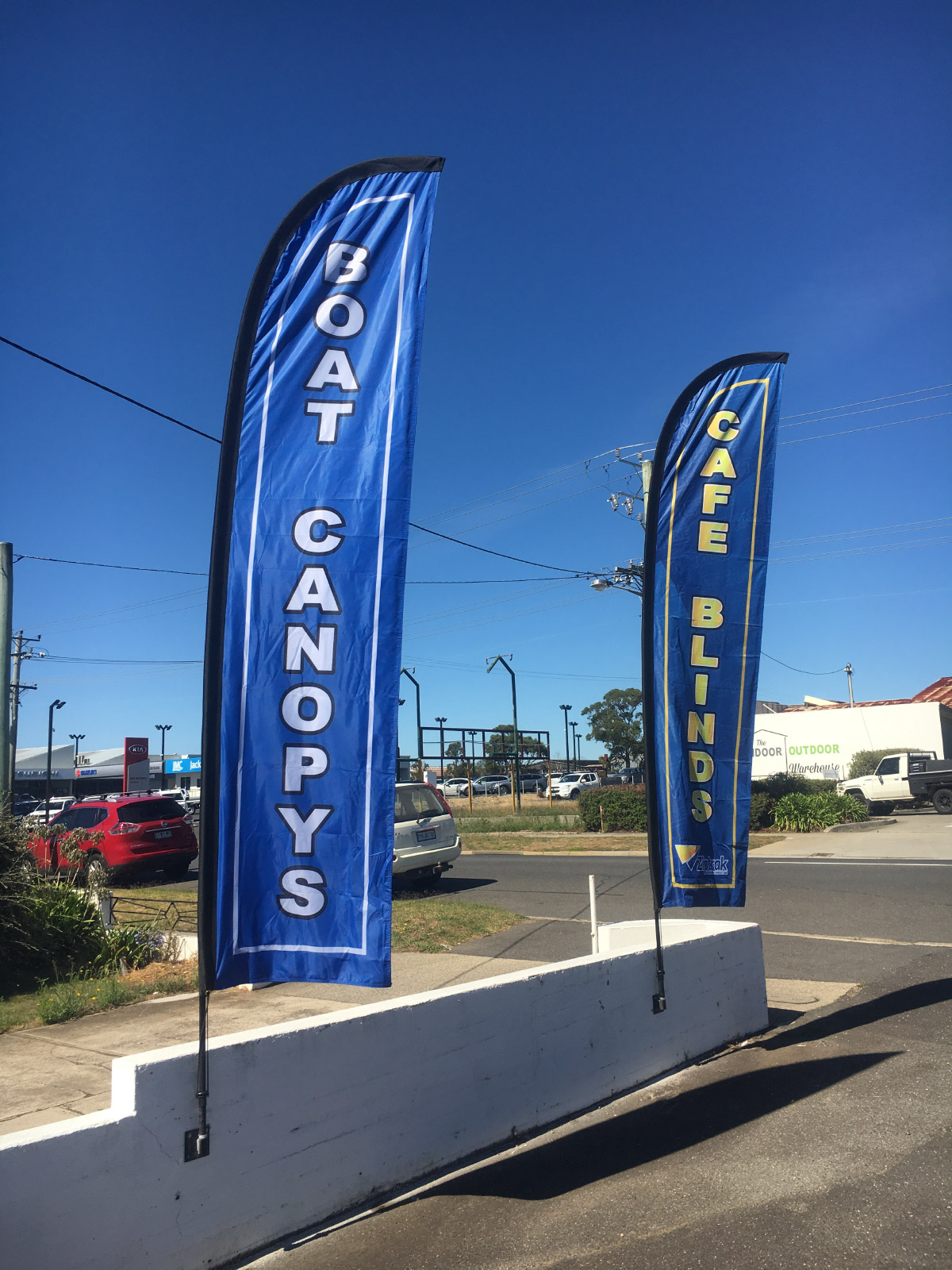 Two blue advertising feather flags reading Boat Canopys and Cafe Blinds